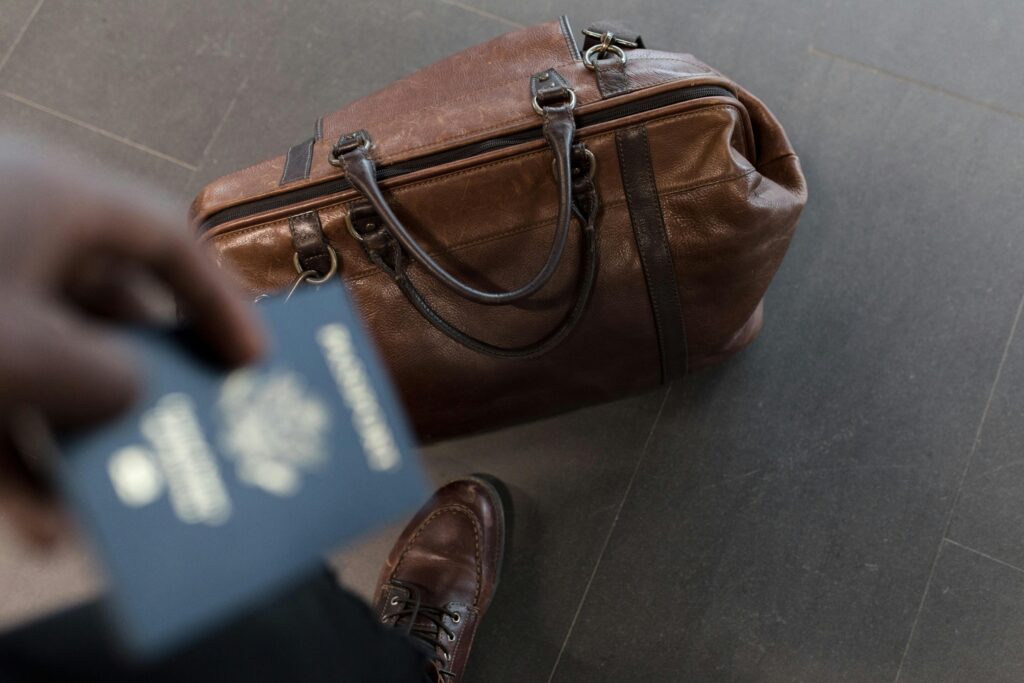 image représentant un sac marron de voyage avec un passport bleu flouté